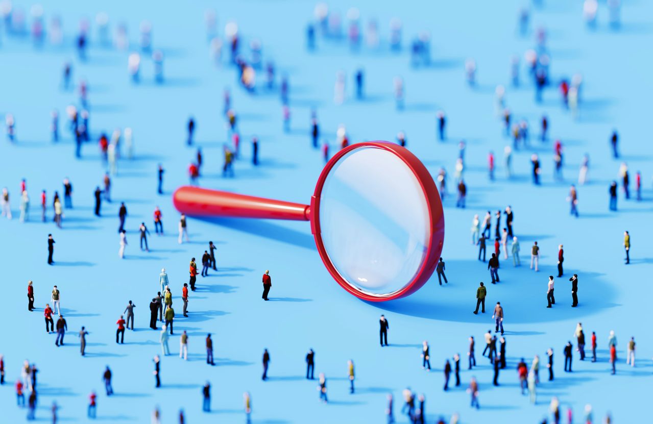 Miniature figures of people and magnifying glass